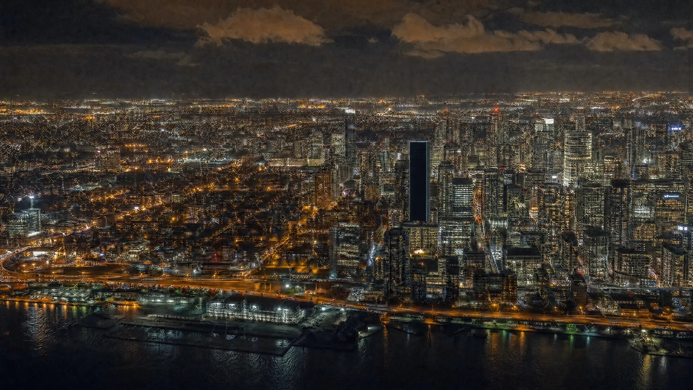 Toronto lit up at night, one tall tower still dark
