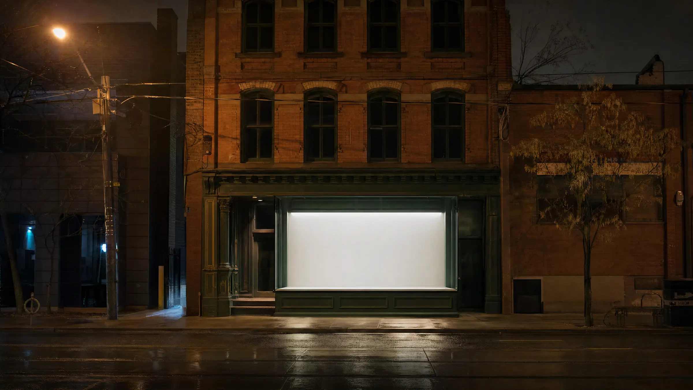 A brick storefront on a Toronto street at night, one window lit