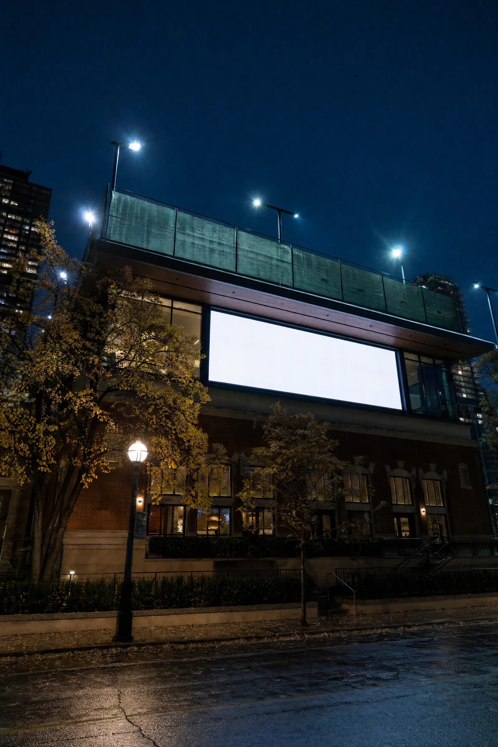 A tennis club building at night, its upper window lit bright